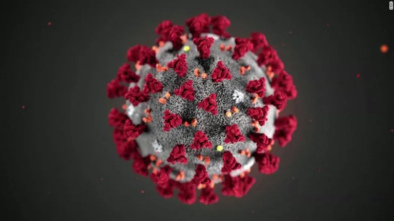 3D rendering of a gray coronavirus particle with red spike proteins on a dark background.